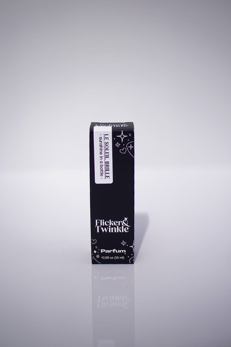Black perfume bottle with 'Flicker & Twinkle' branding on a reflective gray background