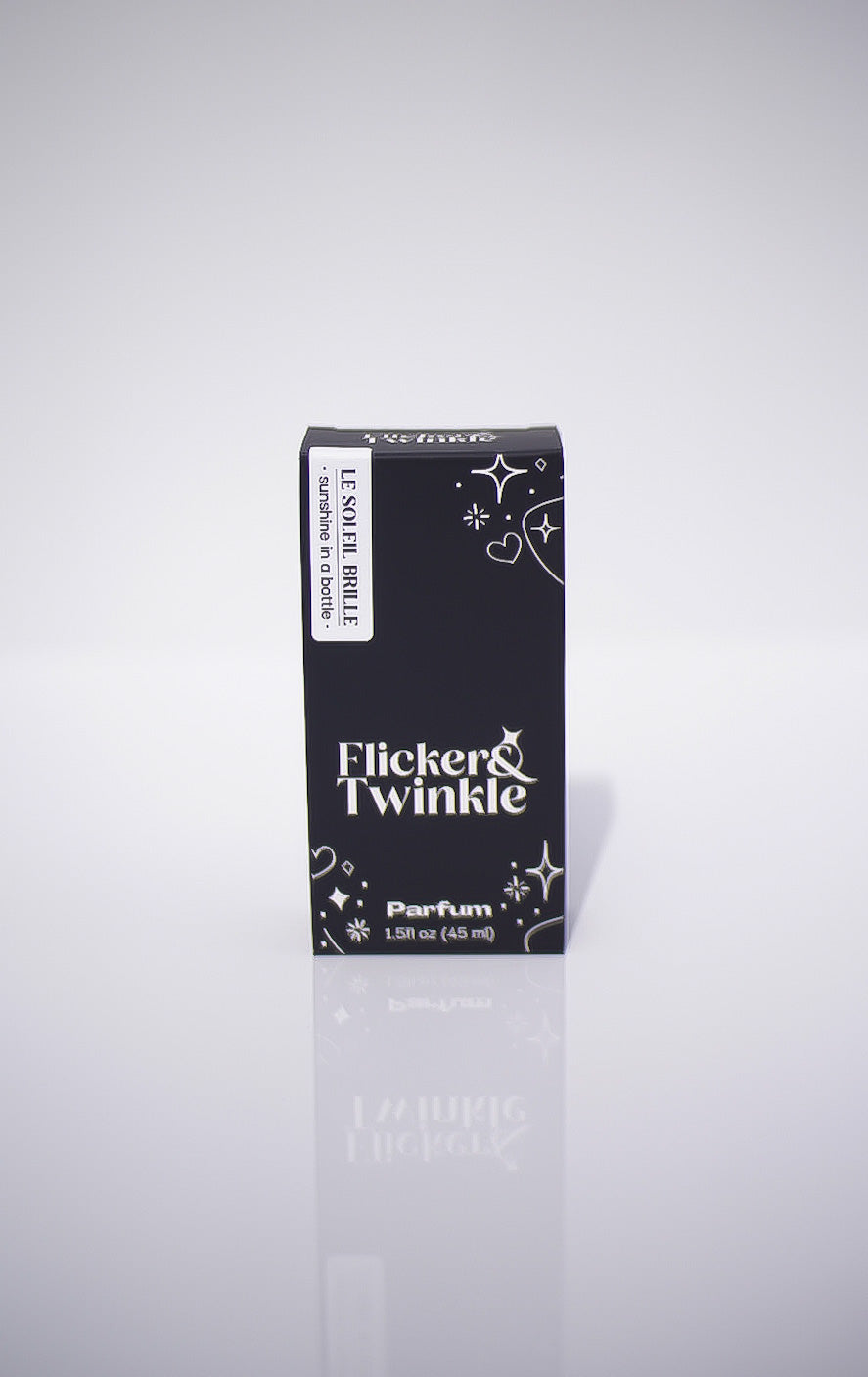 Flicker & Twinkle perfume black packaging on a light gray reflective background