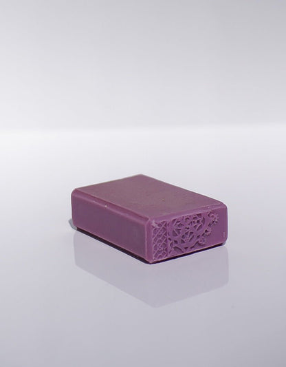 A Blooming Lilac Goats Milk Soap bar with embossing on one end, placed on a white surface.