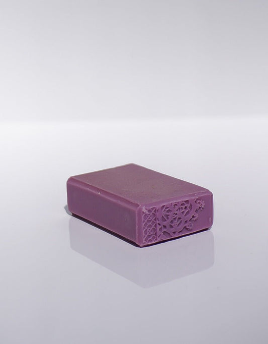 A Blooming Lilac Goats Milk Soap bar with embossing on one end, placed on a white surface.