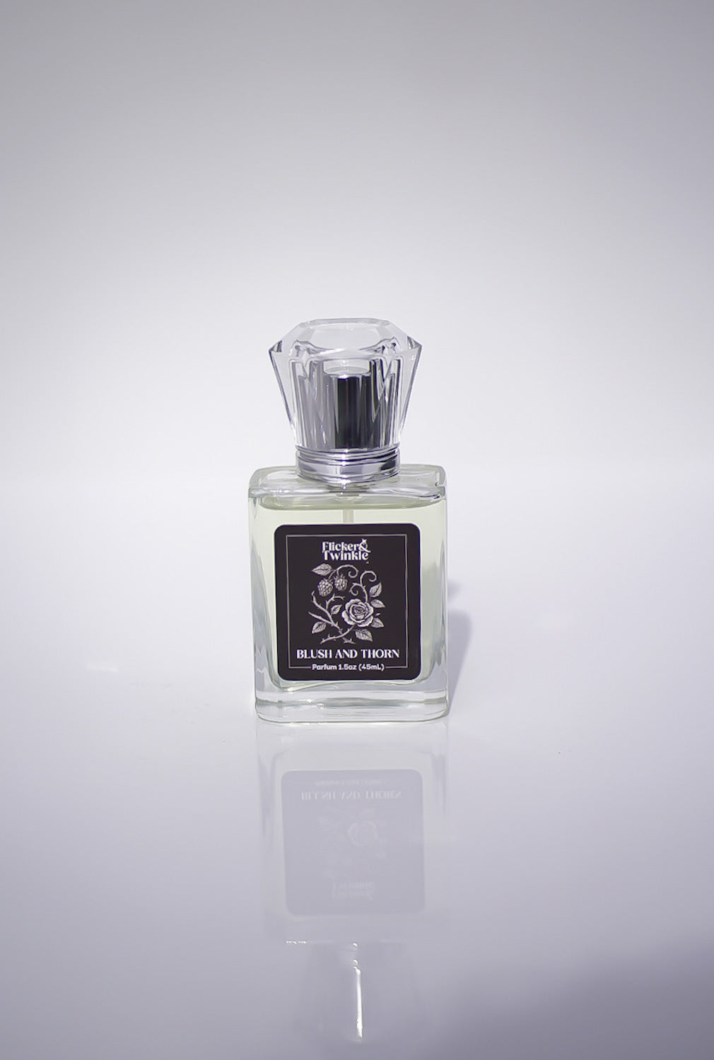 Blush and Thorn Perfume bottle with a label on a white reflective surface