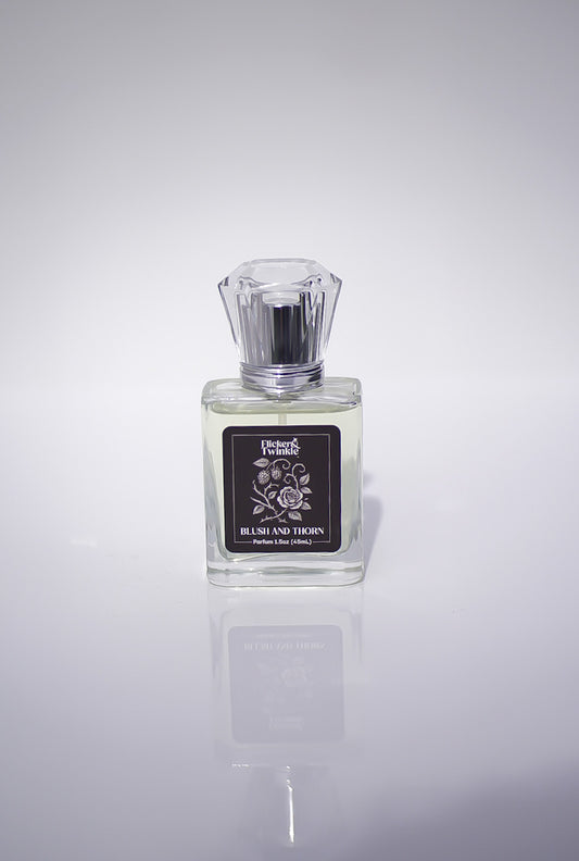 Blush and Thorn Perfume bottle with a label on a white reflective surface