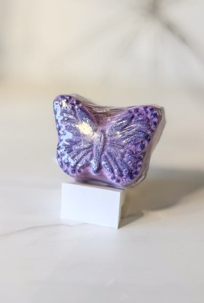 Purple butterfly-shaped bath bomb scent in lavender santal on a white stand with a blurred background