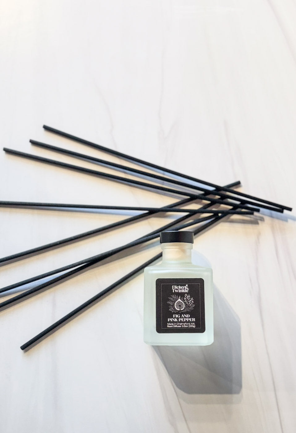 luxury reed diffuser flat lay photo with black fiber reeds scented in fig and pink pepper luxury hotel scent