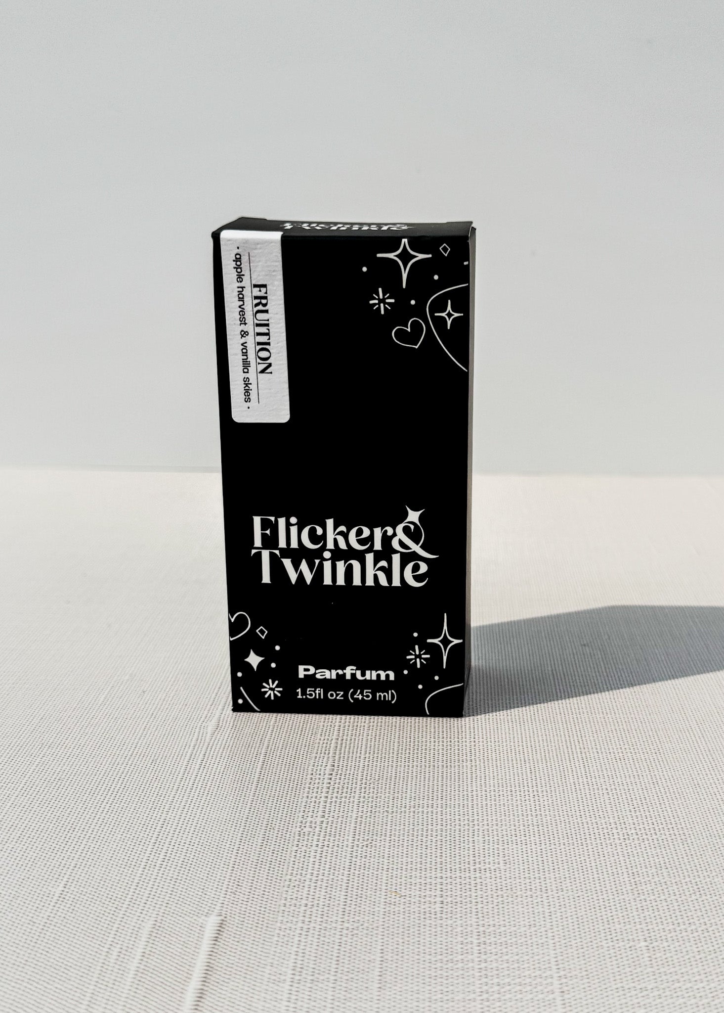 Black box of Flicker & Twinkle Parfum on a light gray background