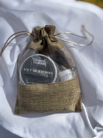 Small round container with a label inside a gold drawstring bag on a white fabric background