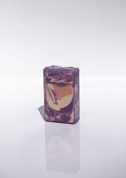 A rectangular bar of Lavender Santal Goats Milk Soap with shea butter on a white surface.