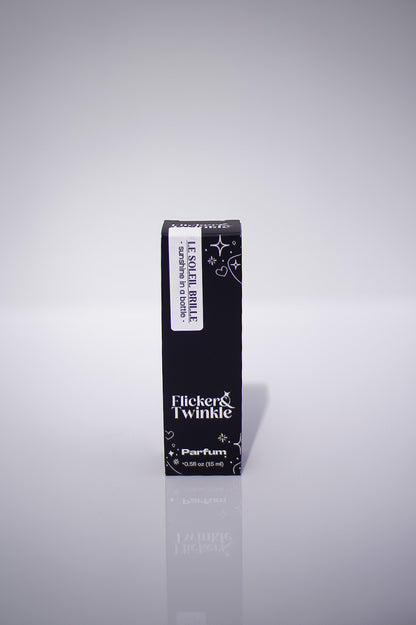Black perfume bottle with 'Flicker & Twinkle' branding on a reflective gray background