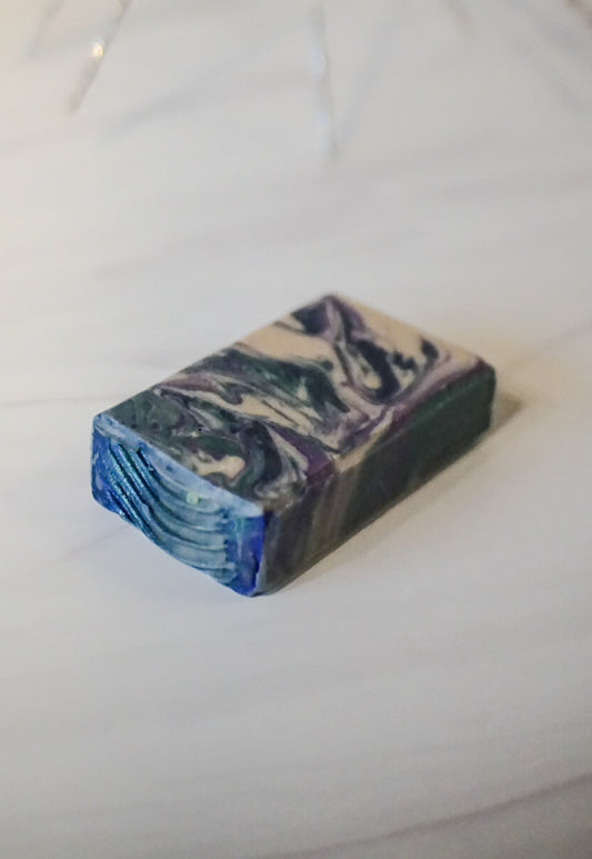 Purple Dark Blue and Dark Green and White Marbled soap bar on a white surface. Goat Milk Soap Scented in Masculine Earthy Fragrance