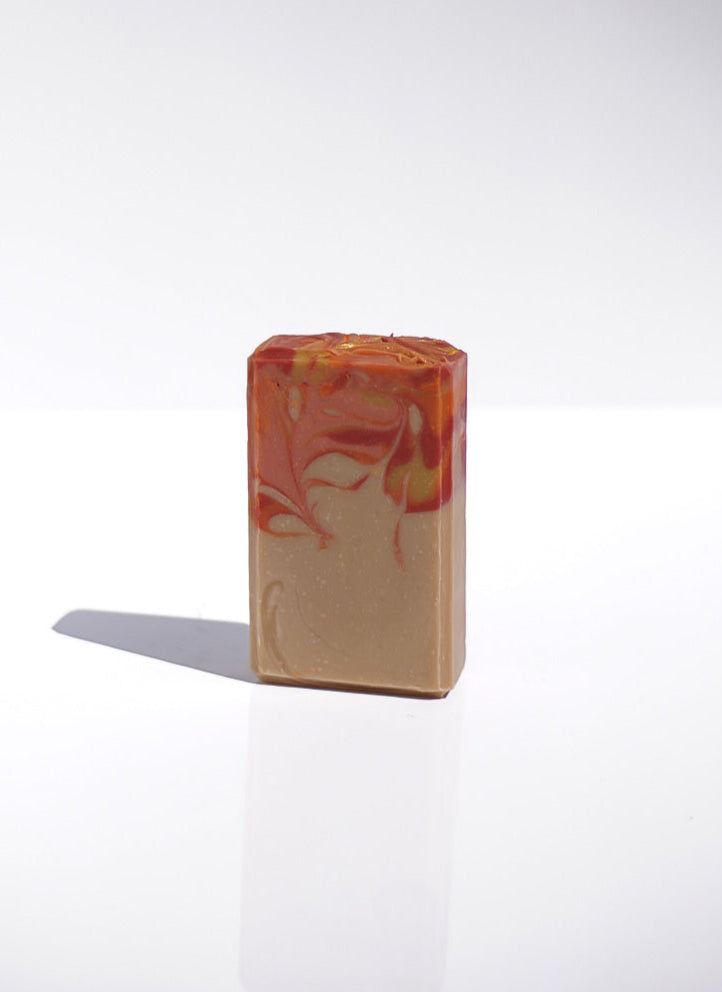 New England Goat Milk Bar of soap with bright autumn colored marbled design on top half of the bar on a white background