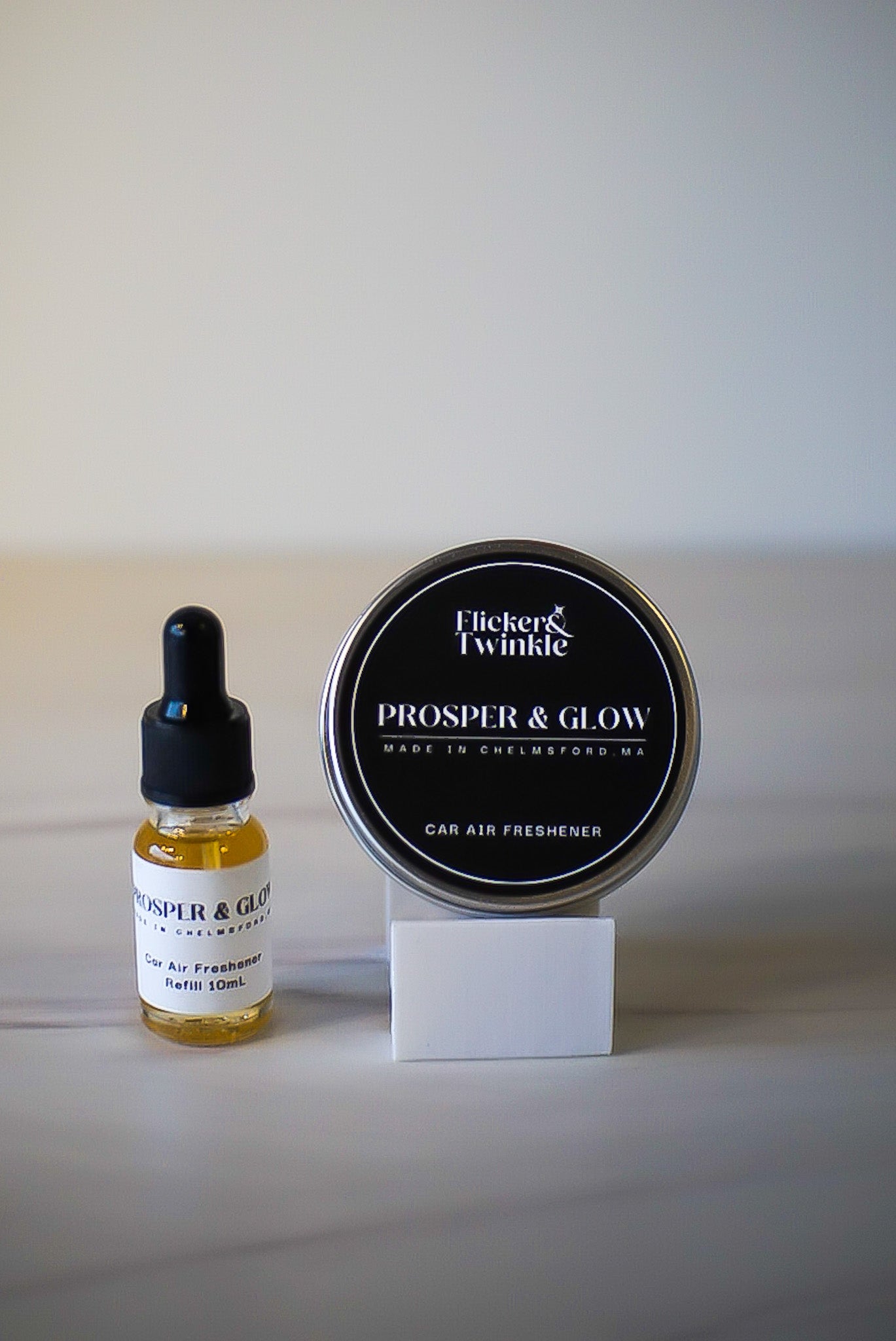 Flicker & Twinkle Prosper & Glow car air freshener bottle and container on a white background