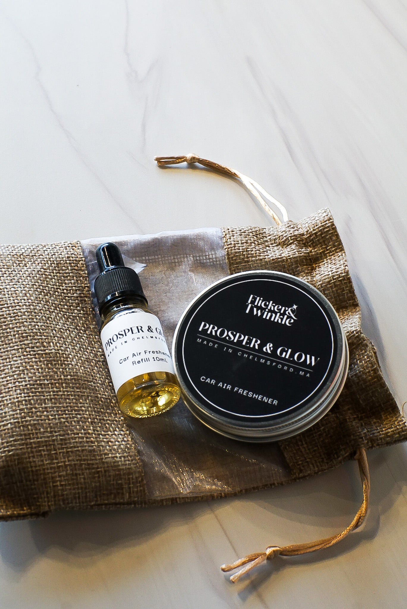 flicker and twinkle car freshener in prosper and glow bayberry holiday scent in a flat lay photo with refill 10mL bottle