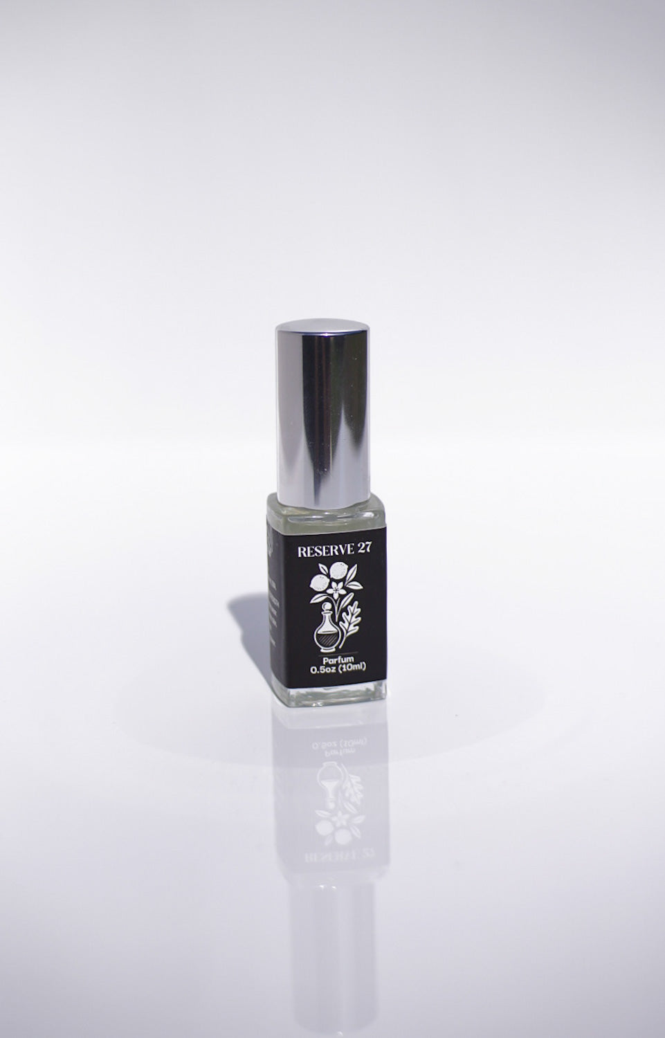 Small 15 mL perfume bottle with a silver cap on a white background that says Reserve 27