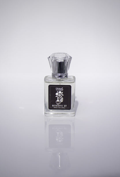 Perfume bottle labeled 'Reserve 27' on a reflective gray surface with a light gray background
