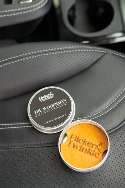 The Woodsman refillable car air freshener in car—open wood diffuser tin with 10 mL refill bottle.