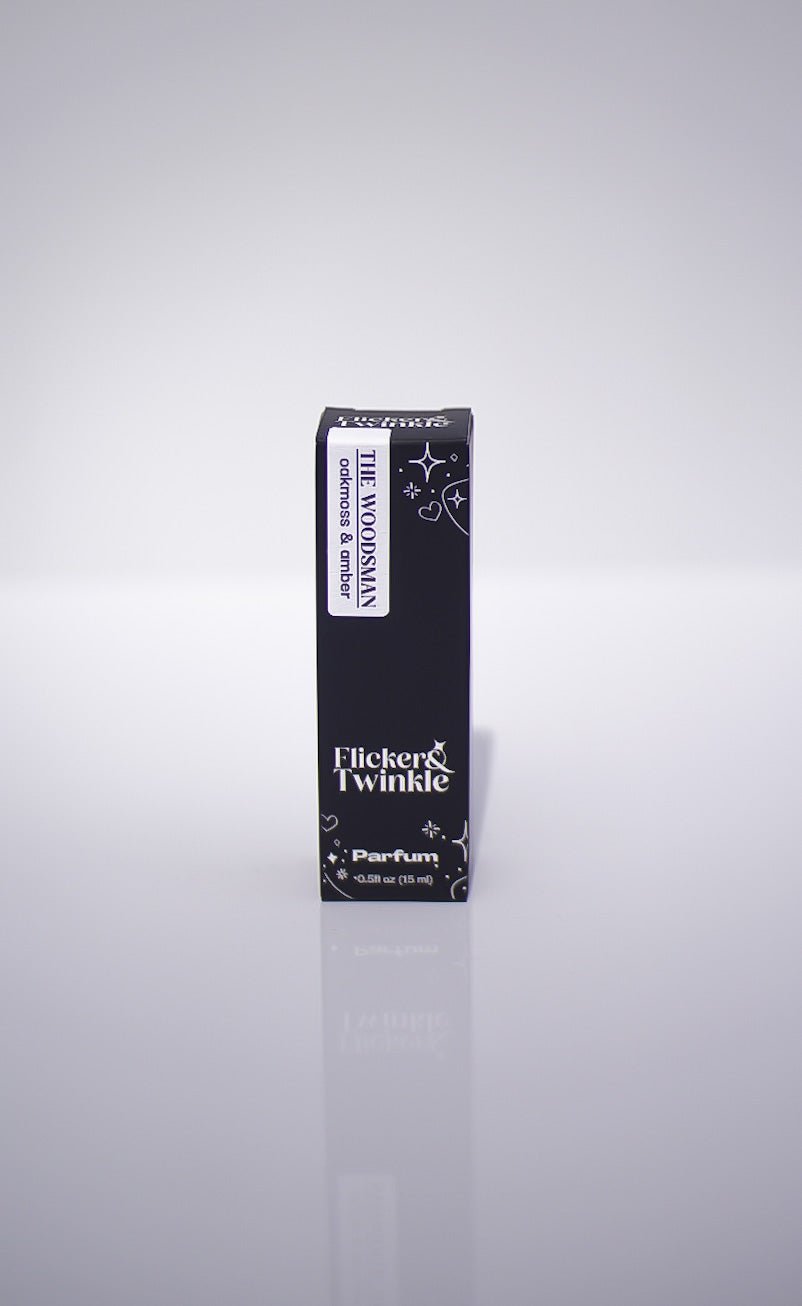 A black box labeled The Woodsman Parfum, an earthy men's scent, stands upright on white.