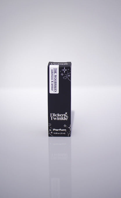 A black box labeled The Woodsman Parfum, an earthy men's scent, stands upright on white.