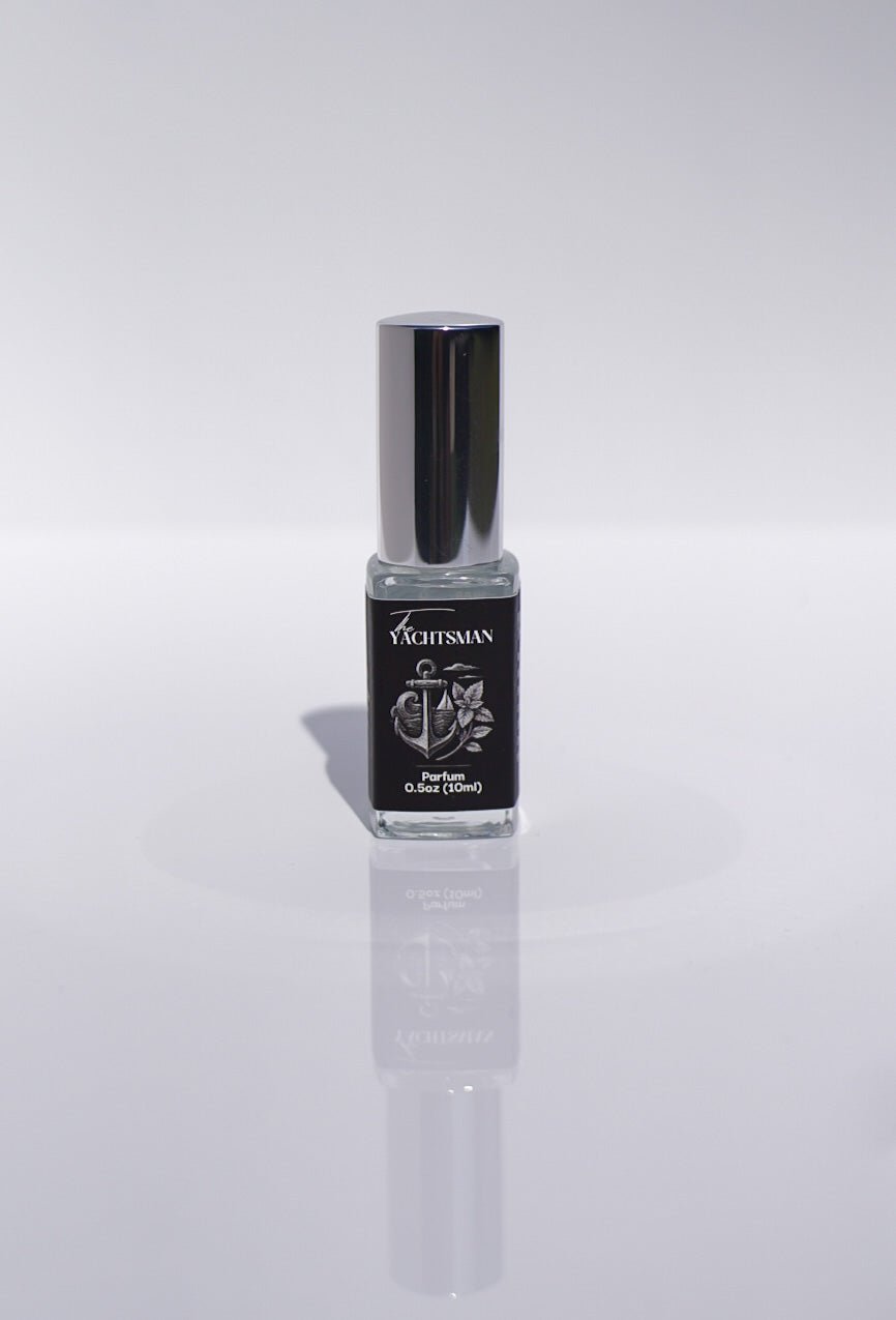 The Yachtsman Perfume, a small luxury bottle with a silver cap, stands on a white surface.