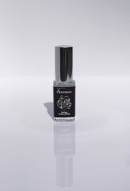 The Yachtsman Perfume, a small luxury bottle with a silver cap, stands on a white surface.