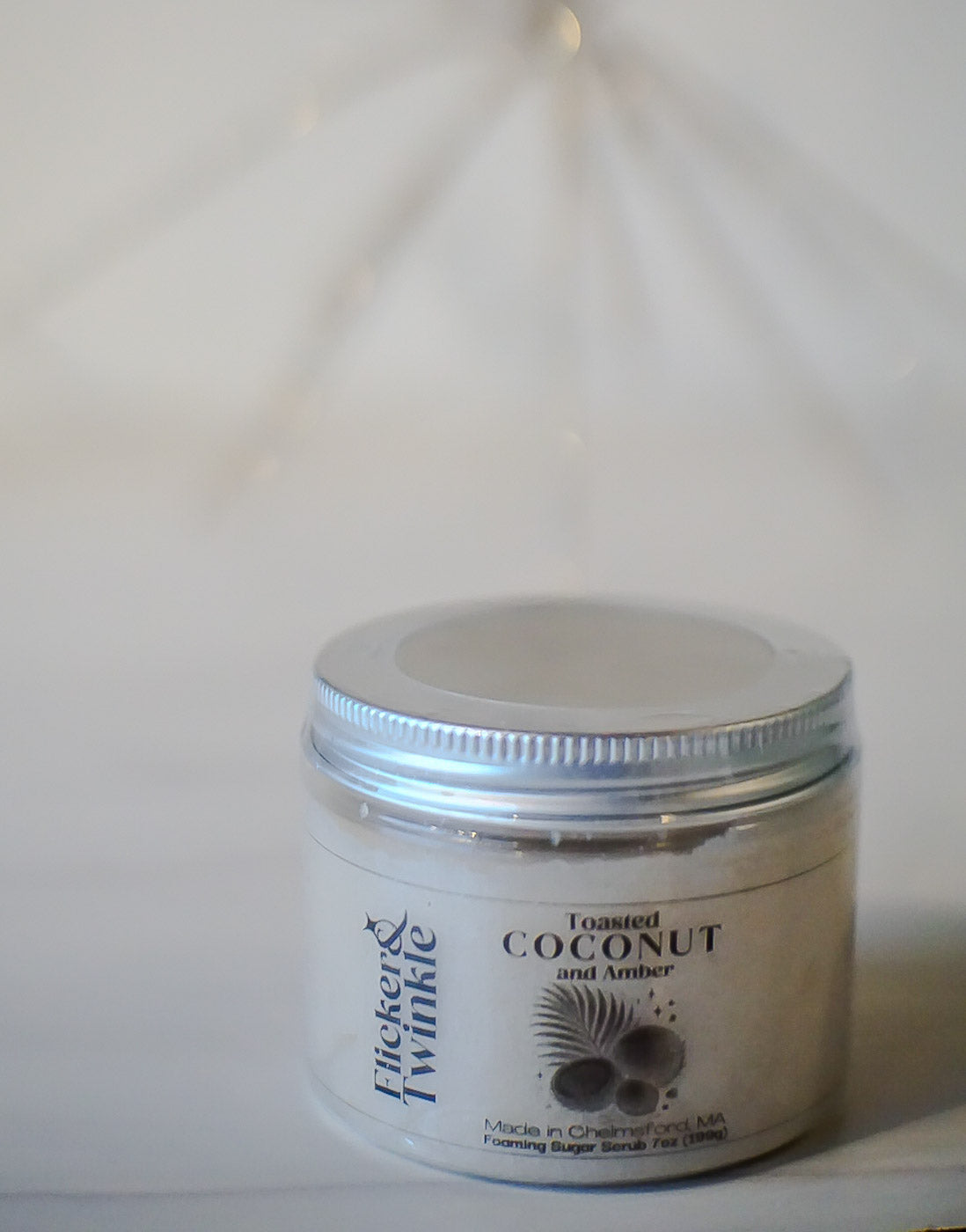 toasted coconut and amber foaming sugar scrub on a neutral white background
