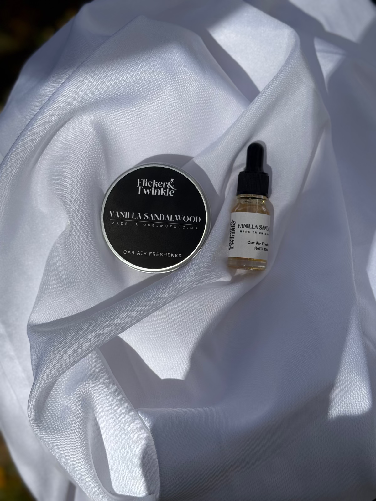 Vanilla sandalwood car air freshener and dropper bottle on white fabric