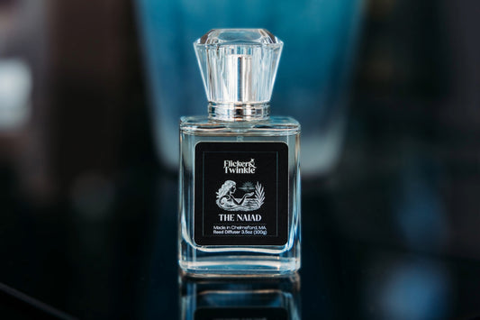Perfume bottle labeled 'The Naiad' by Flicker and Twinkle on a dark background